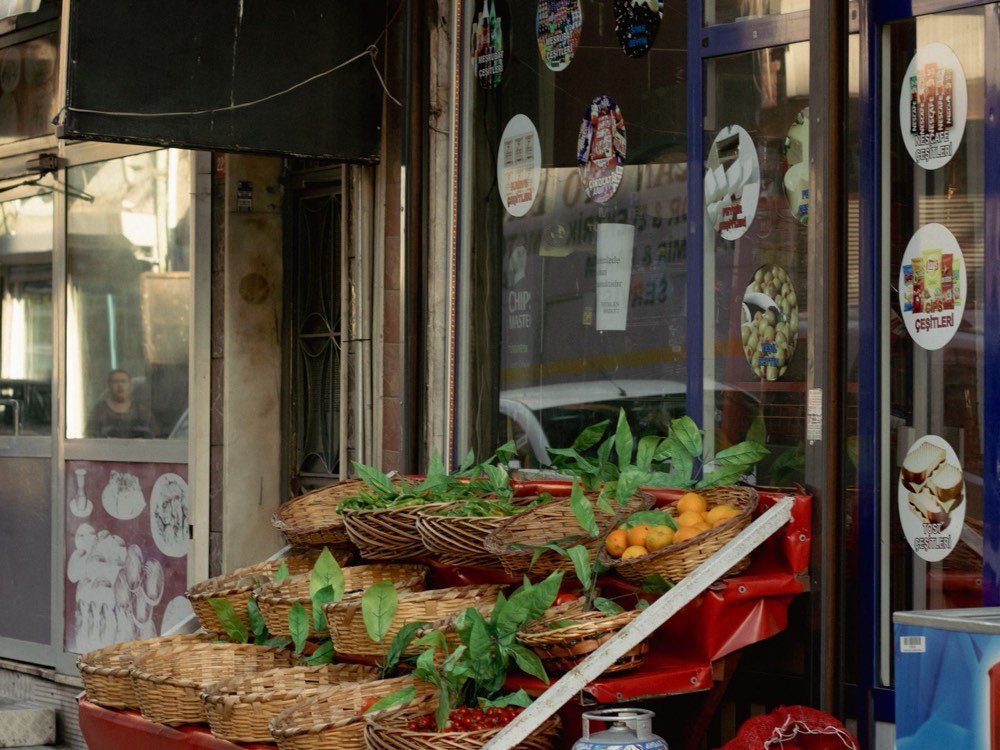 The storefront of a neighborhood international grocery with baskets of fresh produce out front