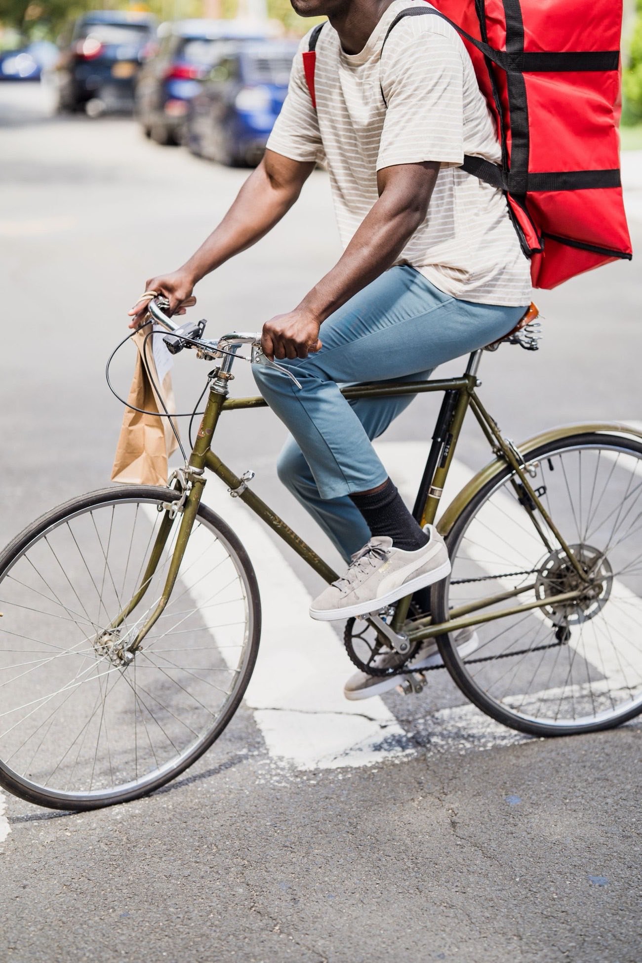 A courier on a bicycle with an insulated delivery bag and a takeout order
