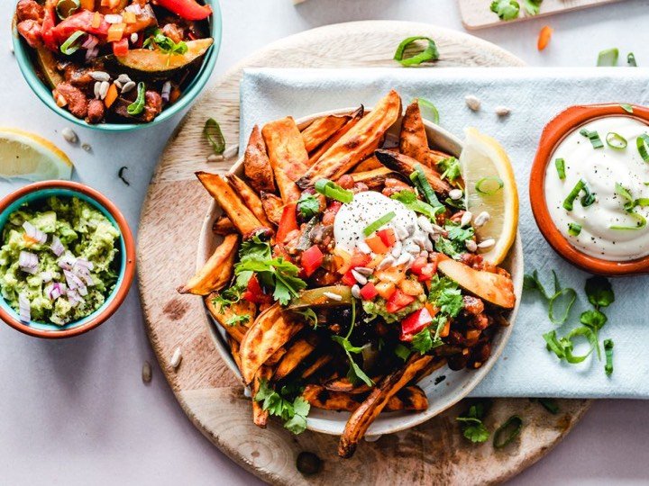 A colorful bowl of loaded fries with fresh toppings