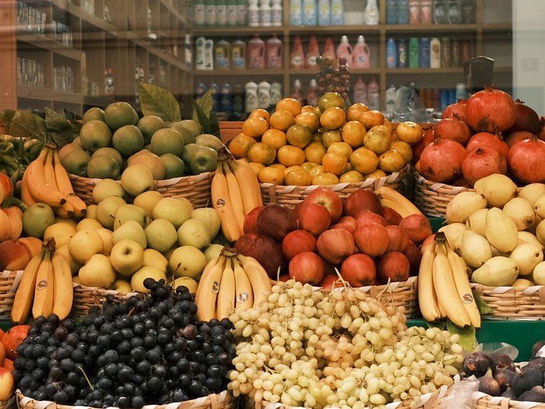 A storefront produce display with baskets of fresh fruit outside a local store